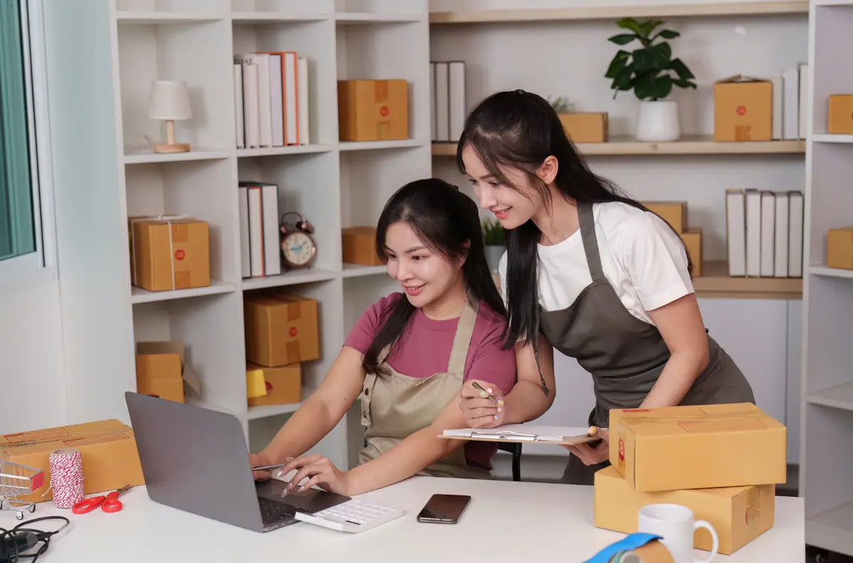 Hai chủ cửa hàng đang kiểm tra đơn hàng trên laptop