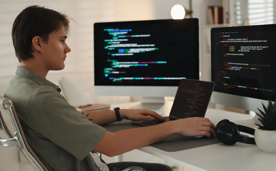 Nhà phát triển đang sửa website tại bàn với hai màn hình