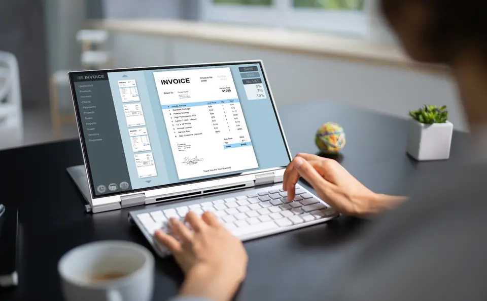 Đang xem hóa đơn trên laptop tại bàn làm việc