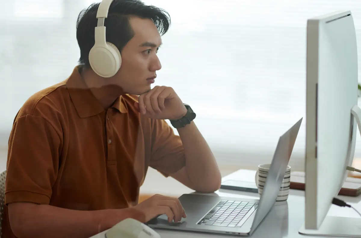 Nhà phát triển đeo tai nghe, đang xem website trên laptop