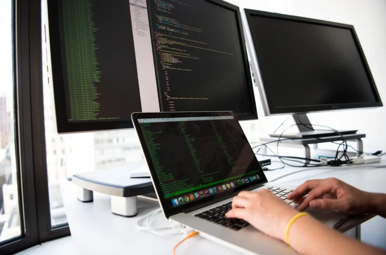 Developer working on code across a laptop and two monitors